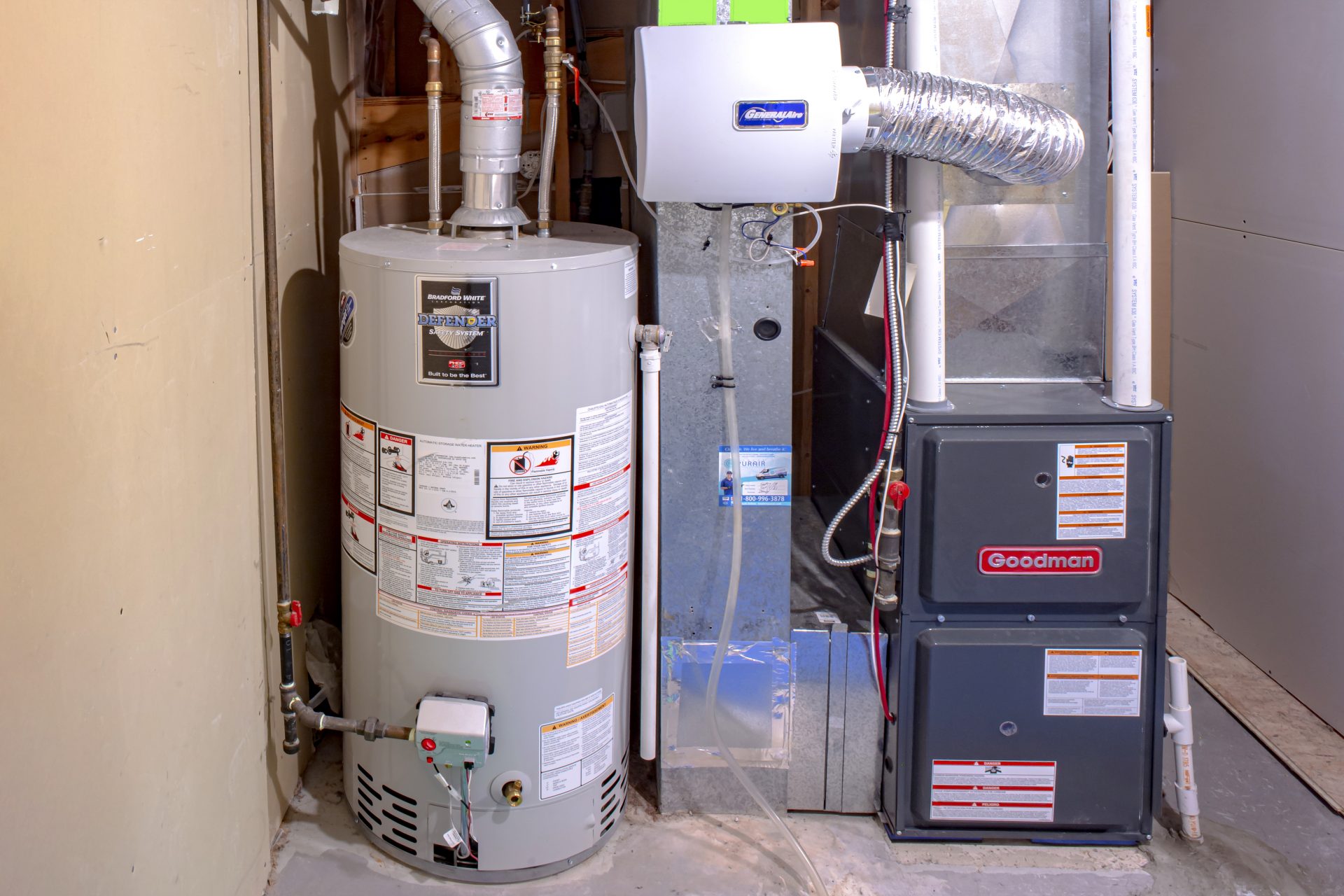 New hot water tank sitting beside a Goodman furnace in an Edmonton-based residential mechanical room.