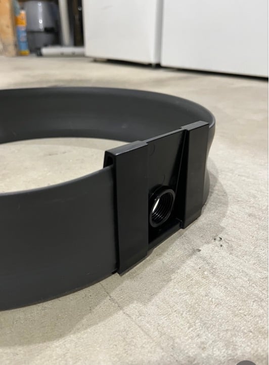 Close-up of a black plastic ring clamp with a threaded metal nut on a concrete floor.