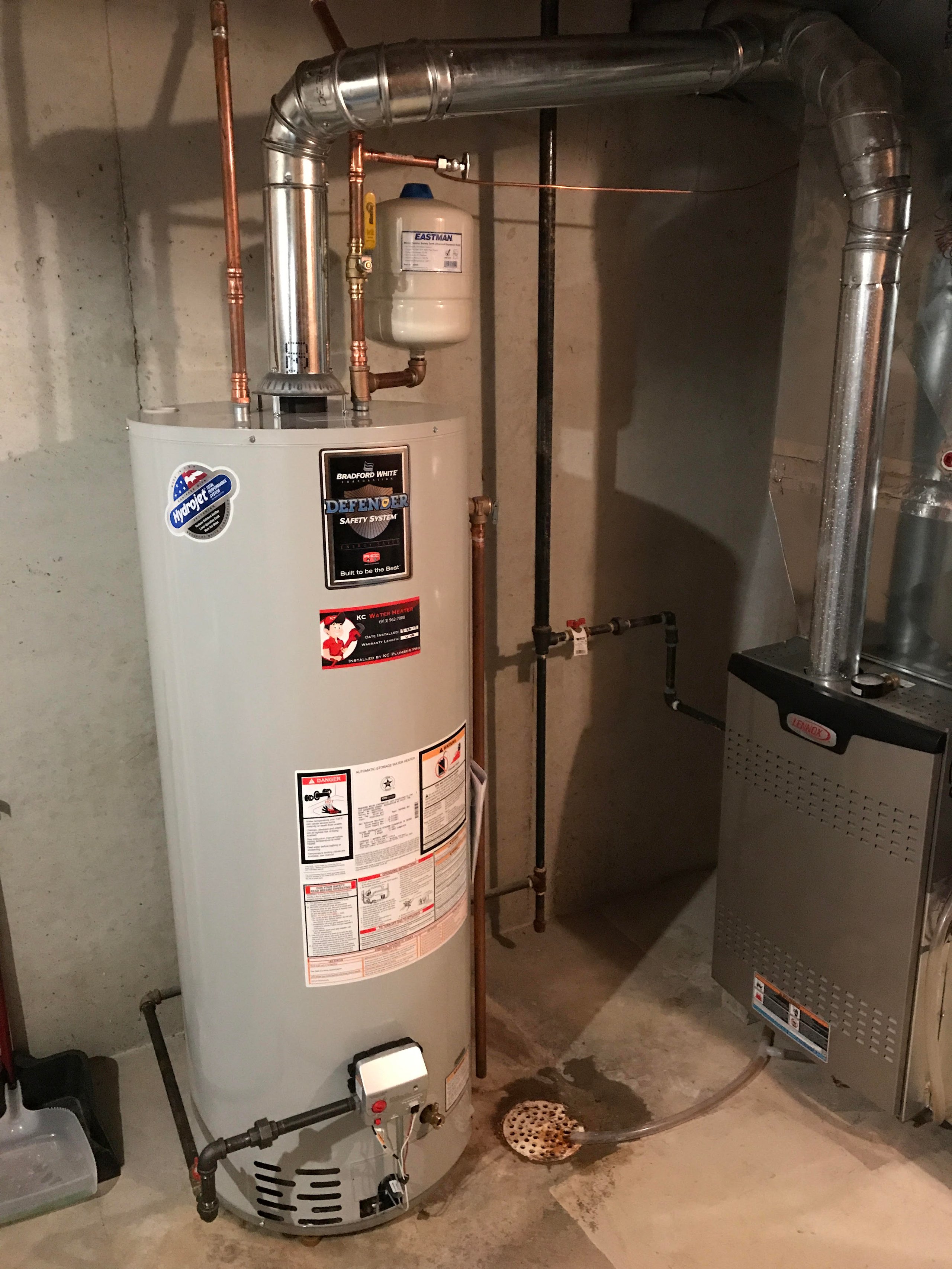 Water heater and furnace installed in a basement with concrete walls and floor.