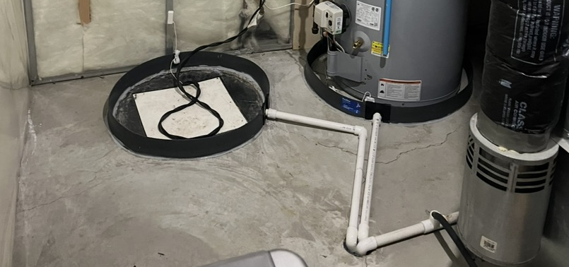 Concrete basement floor with sump pump basin, white PVC pipes, water heater, and HVAC ducting.